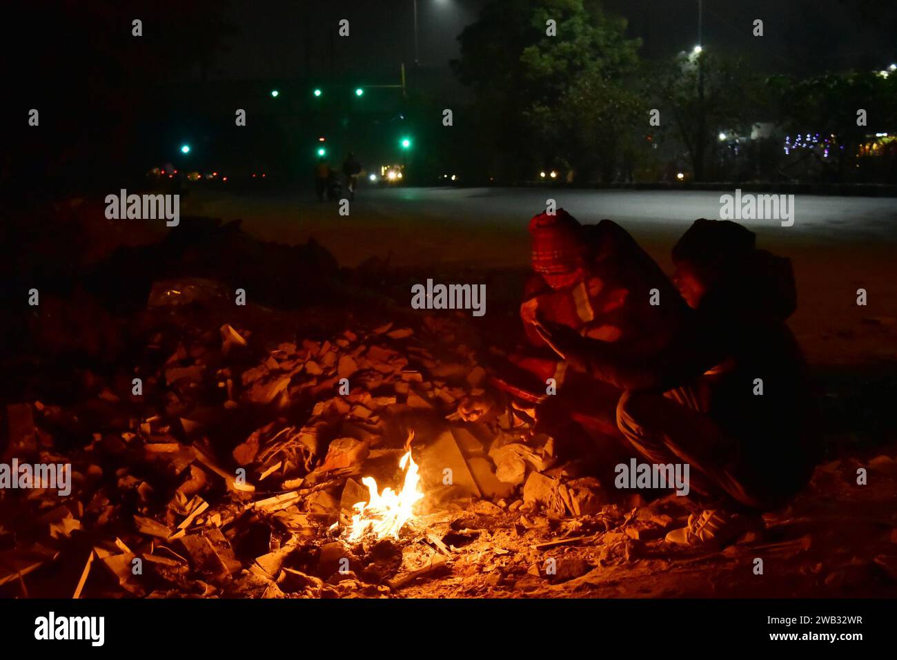 NEW DELHI, INDIA – JANUARY 6: People sitting around bonfire on a cold morning at Khanpur Bus Depot area on January 6, 2024 in New Delhi, India. Foggy morning challenges Delhi-NCR with intensifying cold wave, mercury dips further across North India. (Photo by Sakib Ali/Hindustan Times/Sipa USA ) Stock Photo