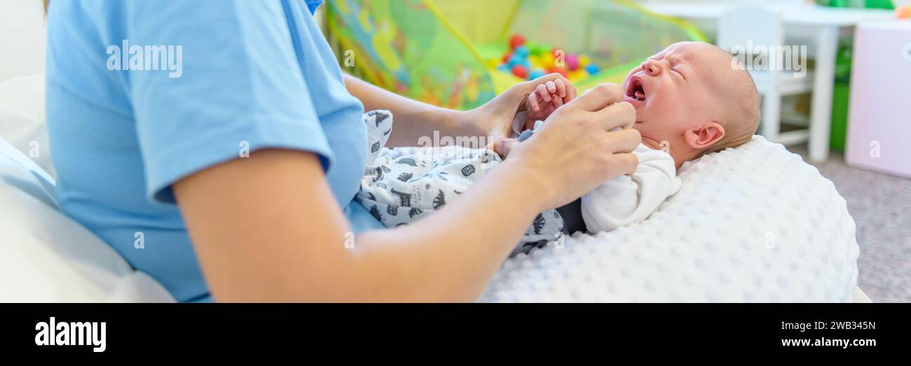 Mother comforting crying newborn. Midwife doing medical check on a newborn baby boy. Stock Photo