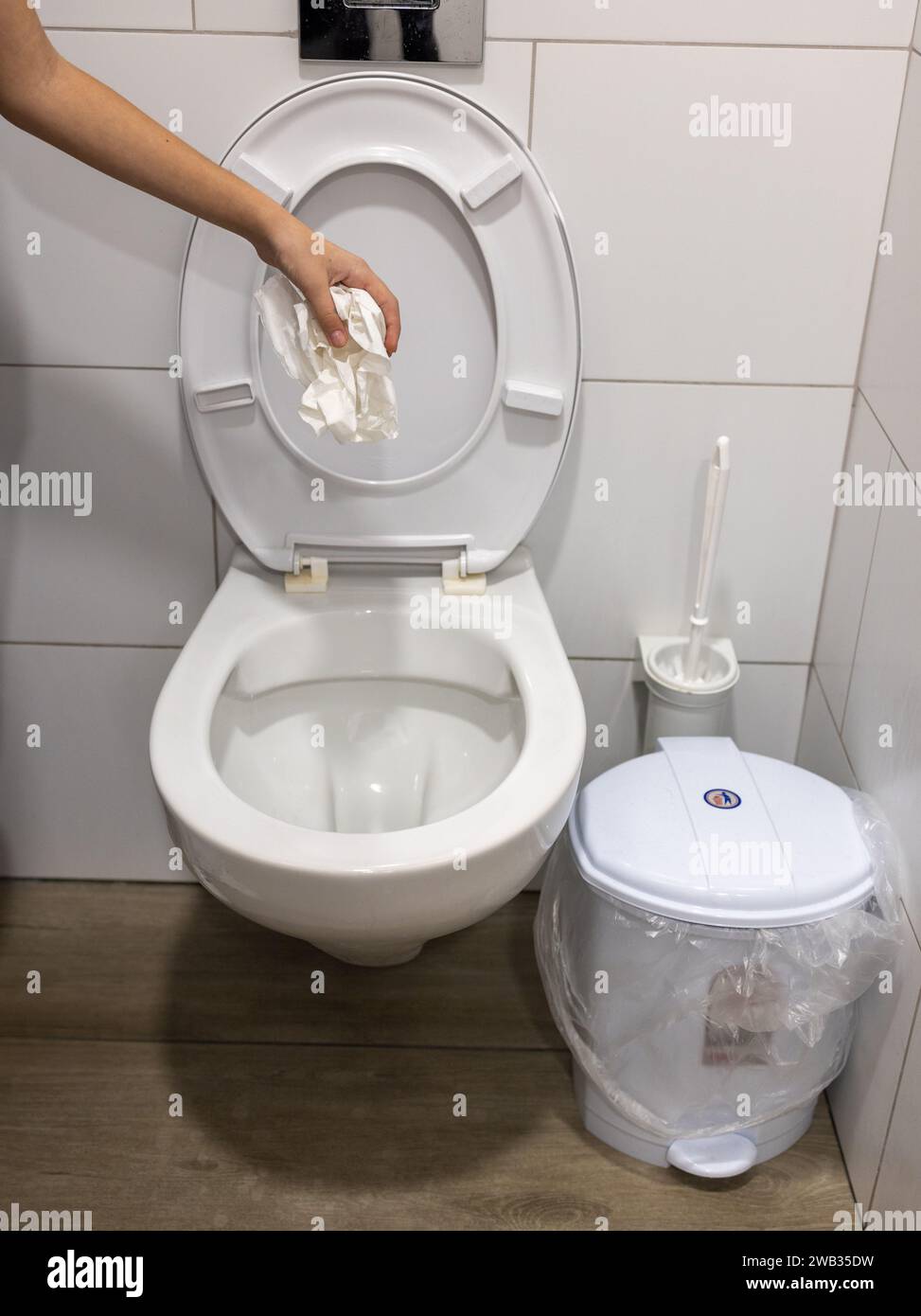 Hand throw toilet paper into the toilet bowl Stock Photo Alamy
