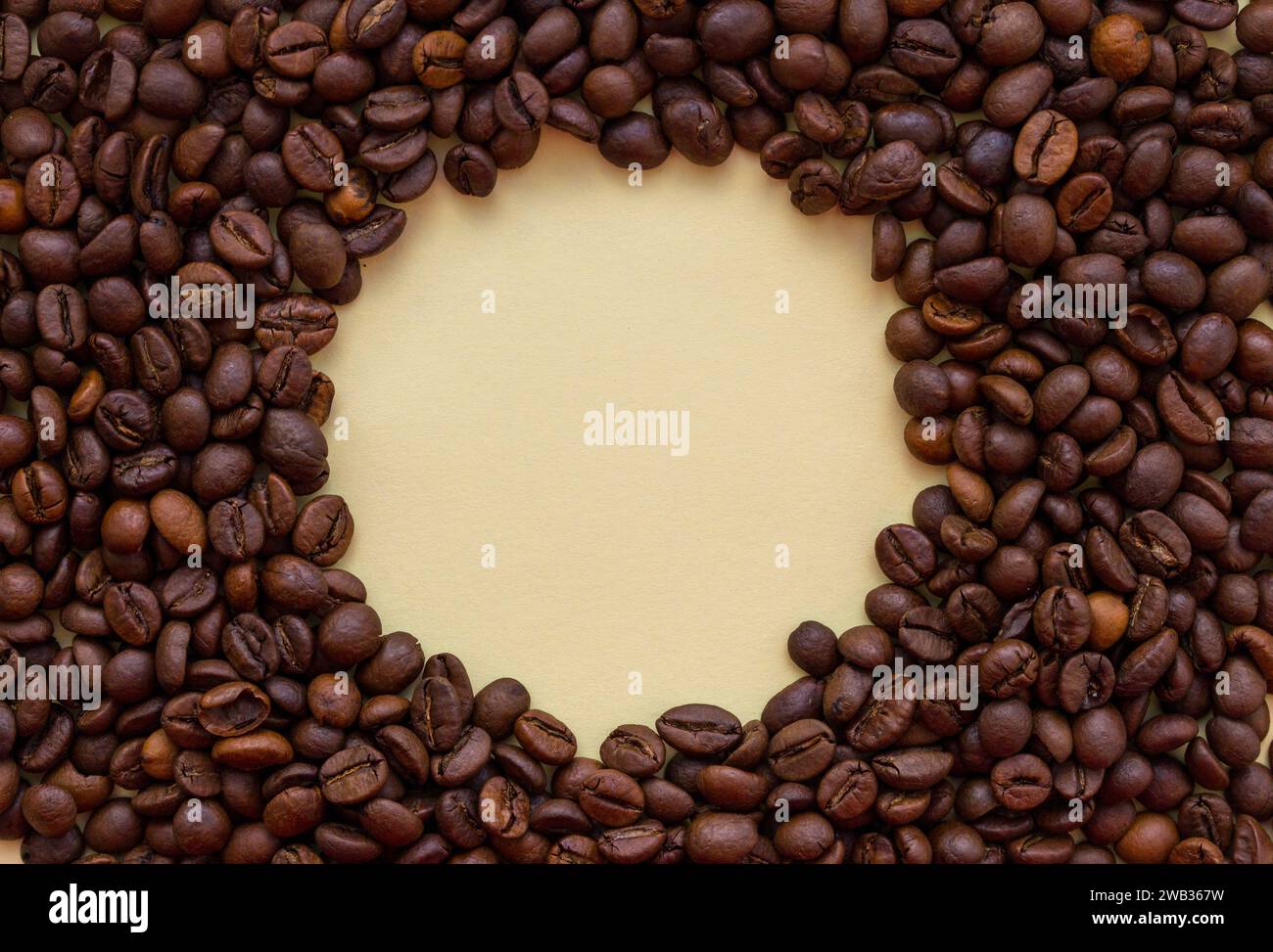 Roasted coffee beans with circle copy space in the middle. Aroma drink concept. Coffee closeup with copy space. Peach Fuzz colour Stock Photo