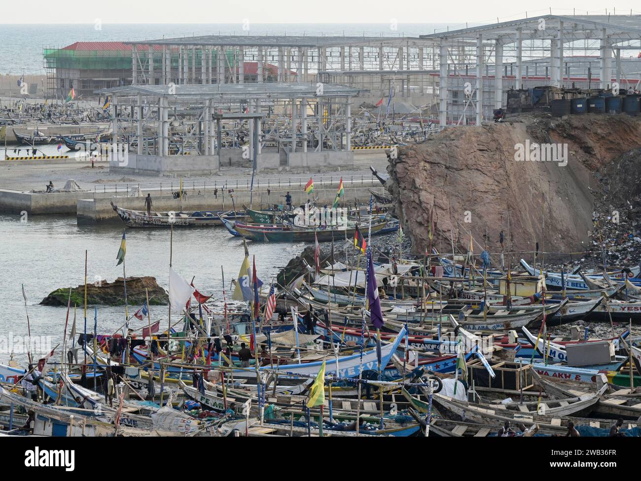 GHANA, Accra, Jamestown, old fishing port and behind construction site of new fishing harbour by chinese company CRCC China Railway Construction Corporation Limited and China Aid  / GHANA, Accra, alter Fischereihafen und hinten Bau eines neuen Fischerei Hafen mit Piers, Fischverarbeitungs- und Kühlhallen durch chinesische Baufirma CRCC und China Aid in Jamestown Stock Photo