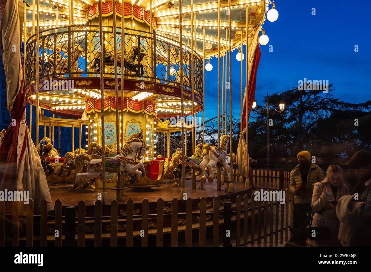A crowd watching a illuminated bunk carrousel during blue hour in the