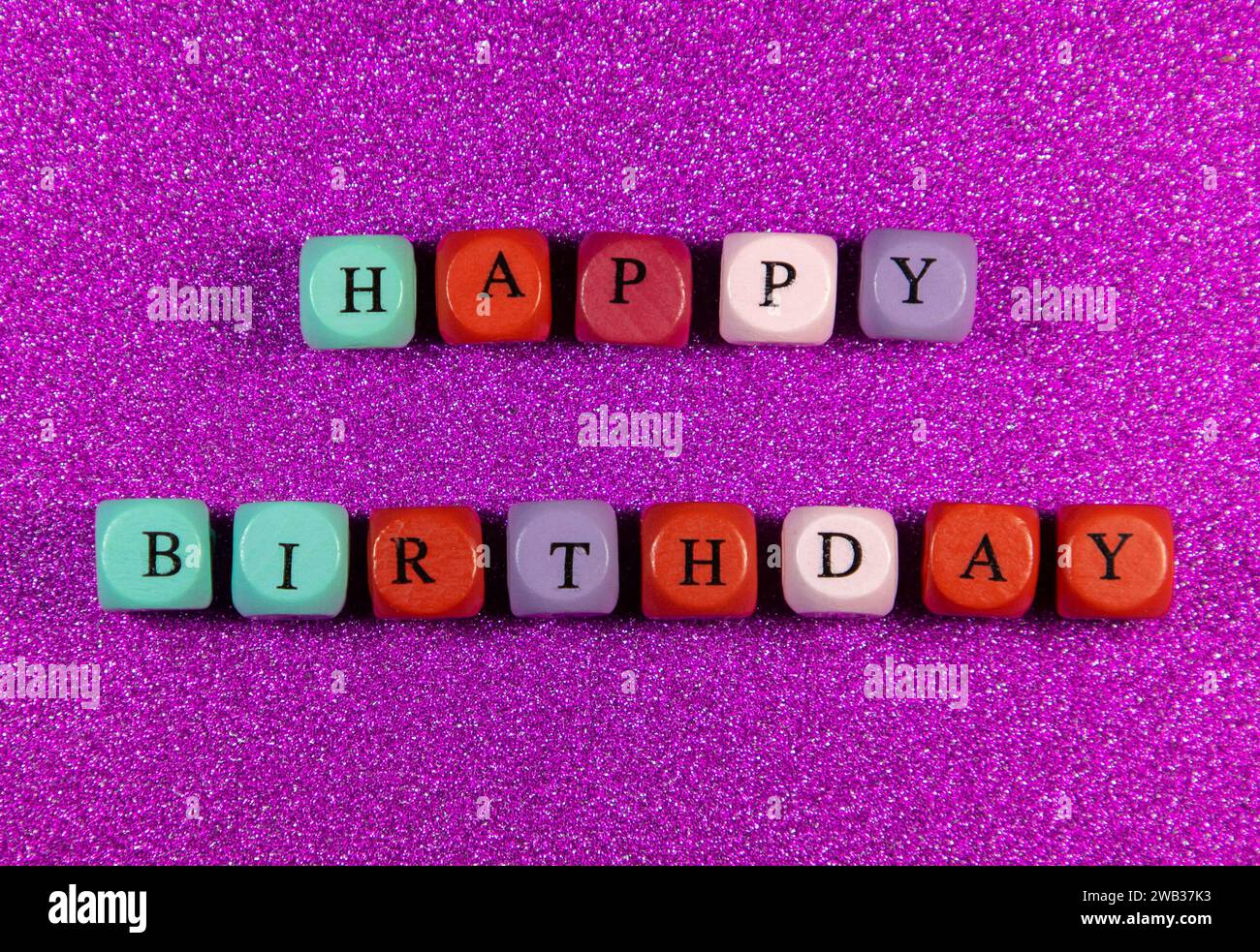 The phrase Happy Birthday written with colorful cubic beads on a purple background Stock Photo