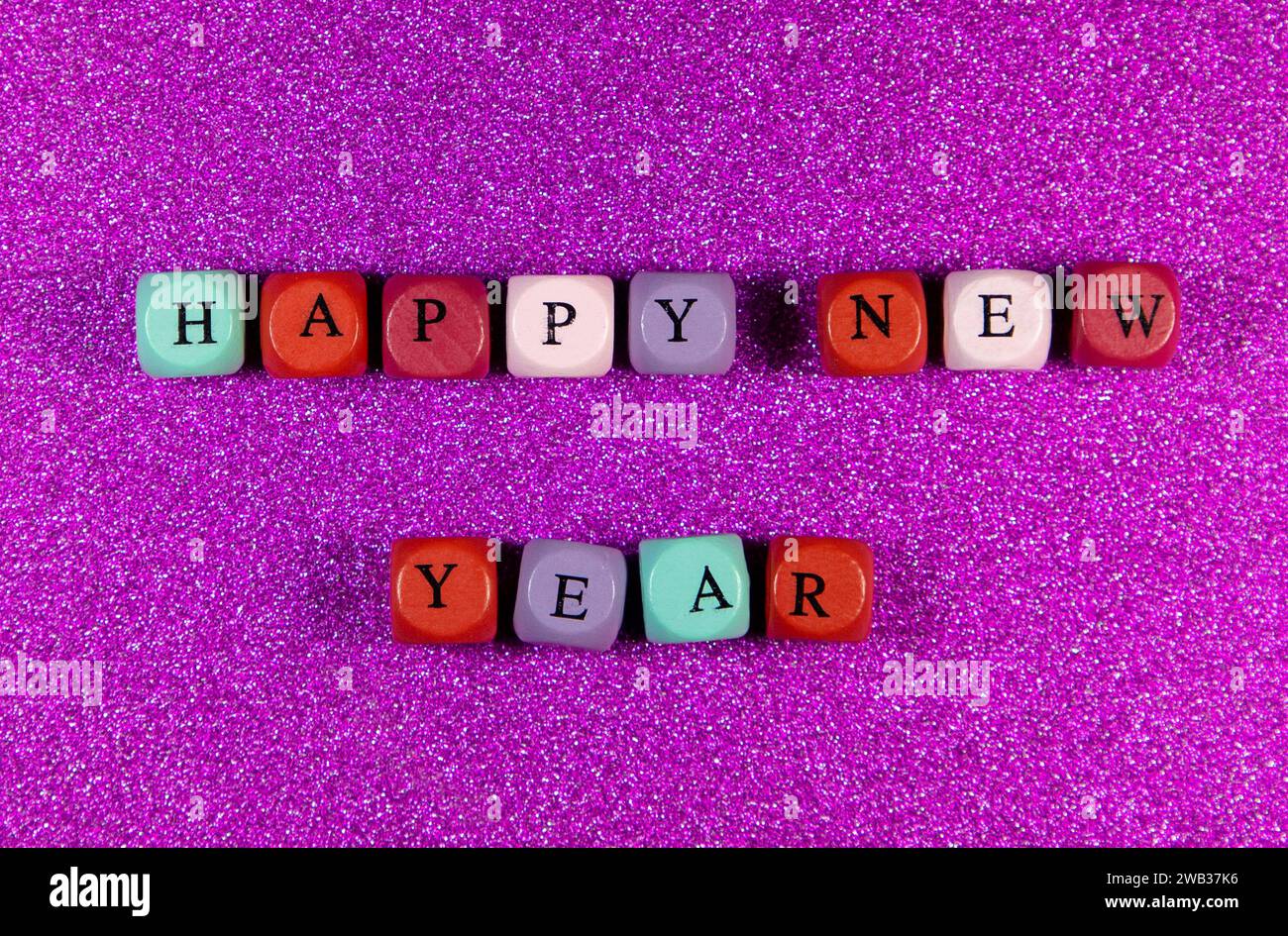 The phrase Happy New Year written with colorful cubic beads on a purple background Stock Photo