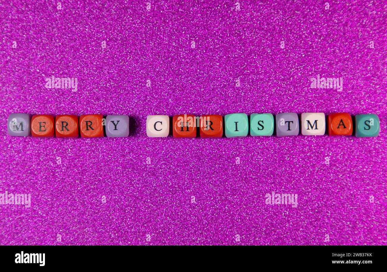 The phrase Merry Christmas written with colorful cubic beads on a purple background Stock Photo