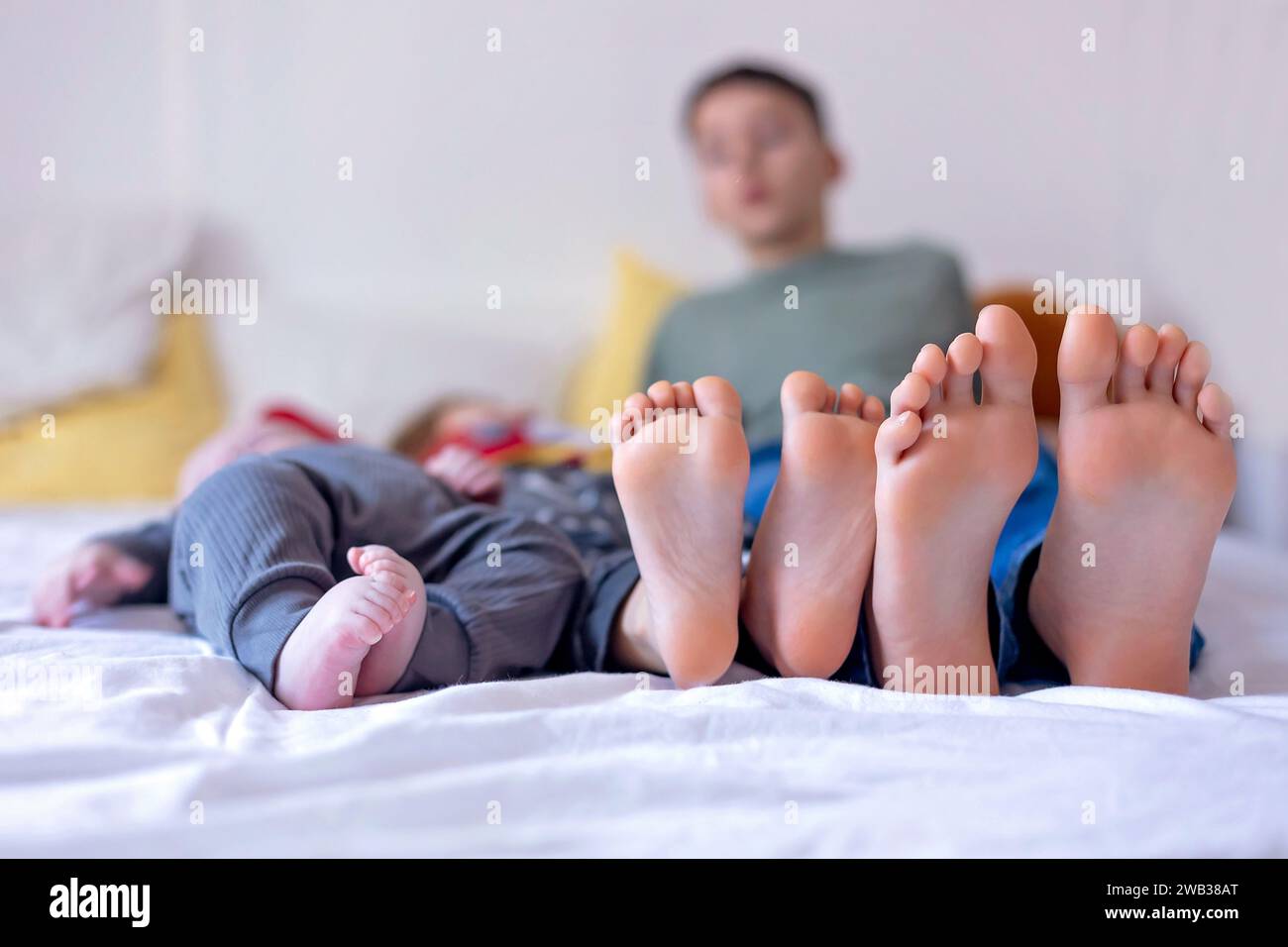 Chlildren feet, little baby boy and older brothers feet, baby lie down in bed in the afternoon Stock Photo