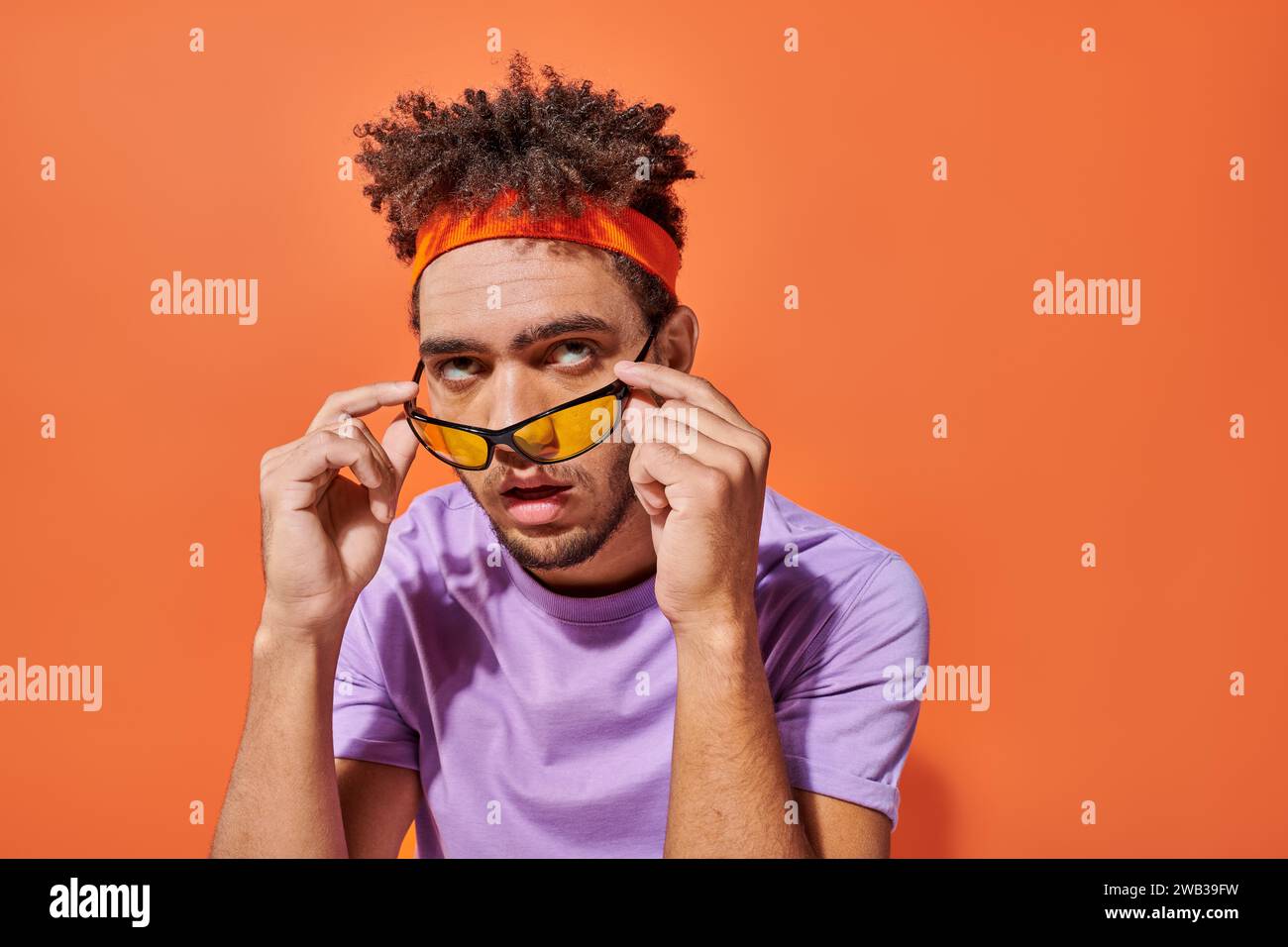 annoyed african american man in eyeglasses and headband rolling eyes on