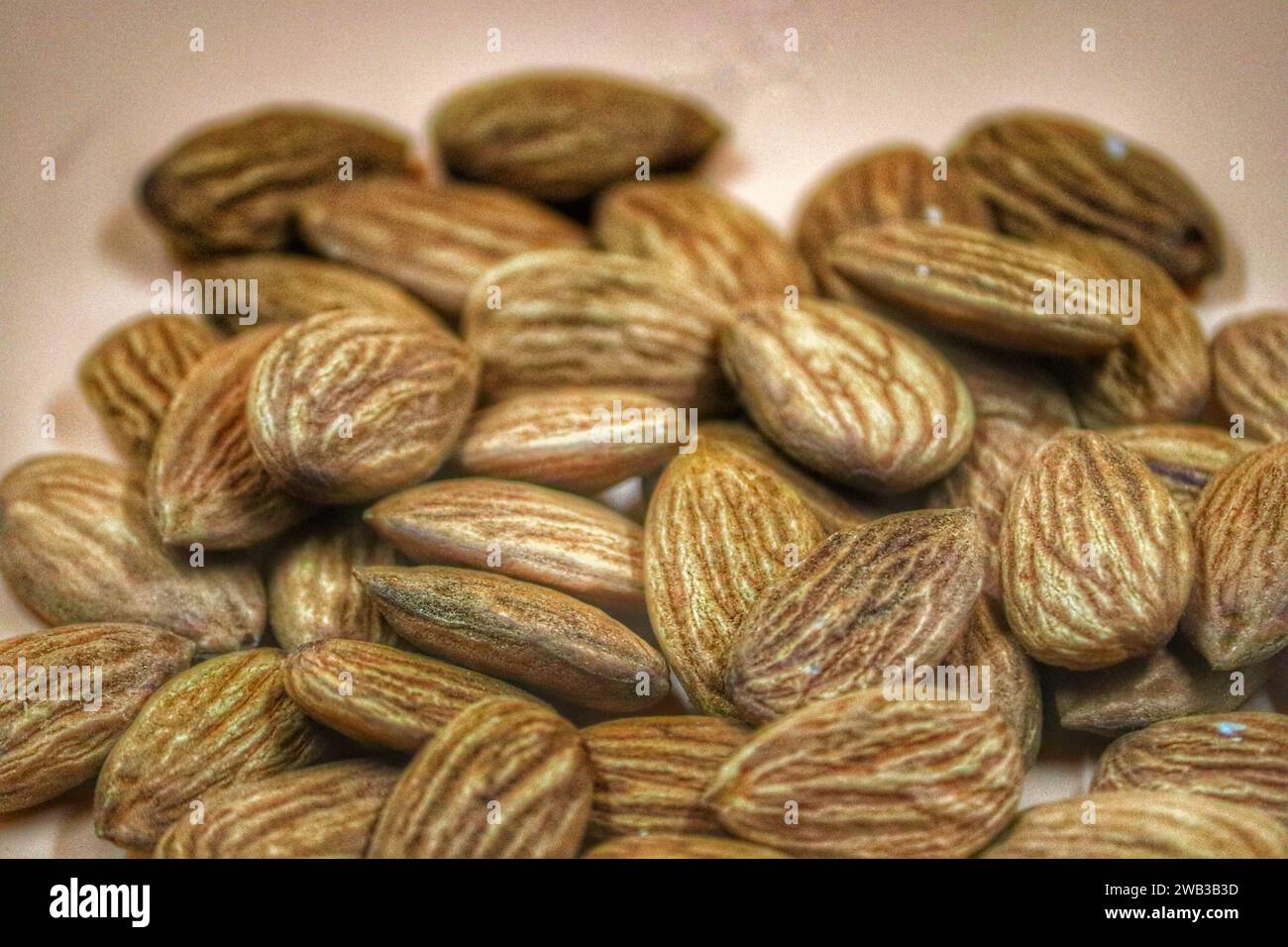 A closeup of a pile of almonds on a beige background. Stock Photo