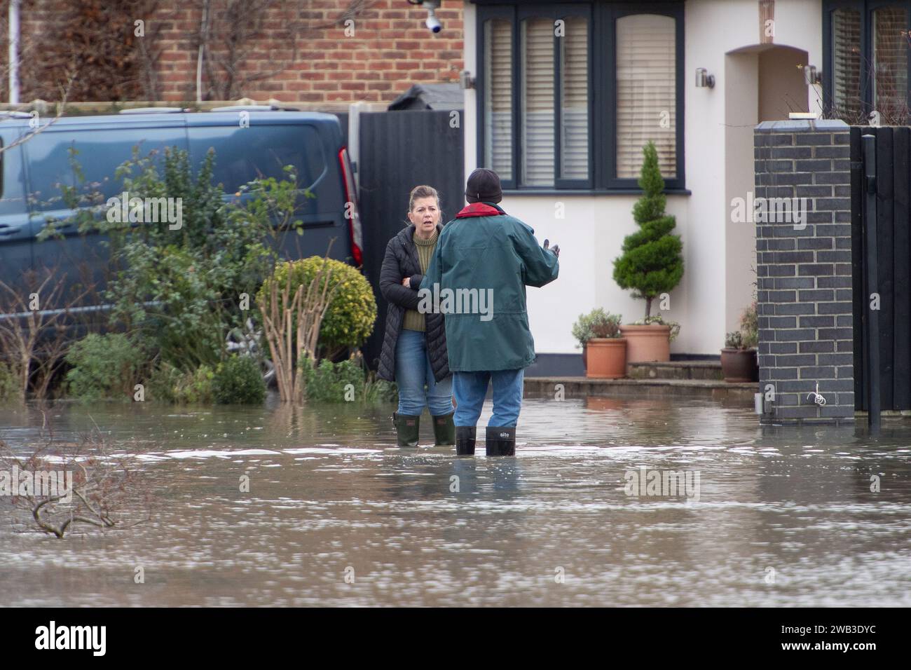 Sunnymeads, UK. 8th January, 2024. A resident wades through a flooded