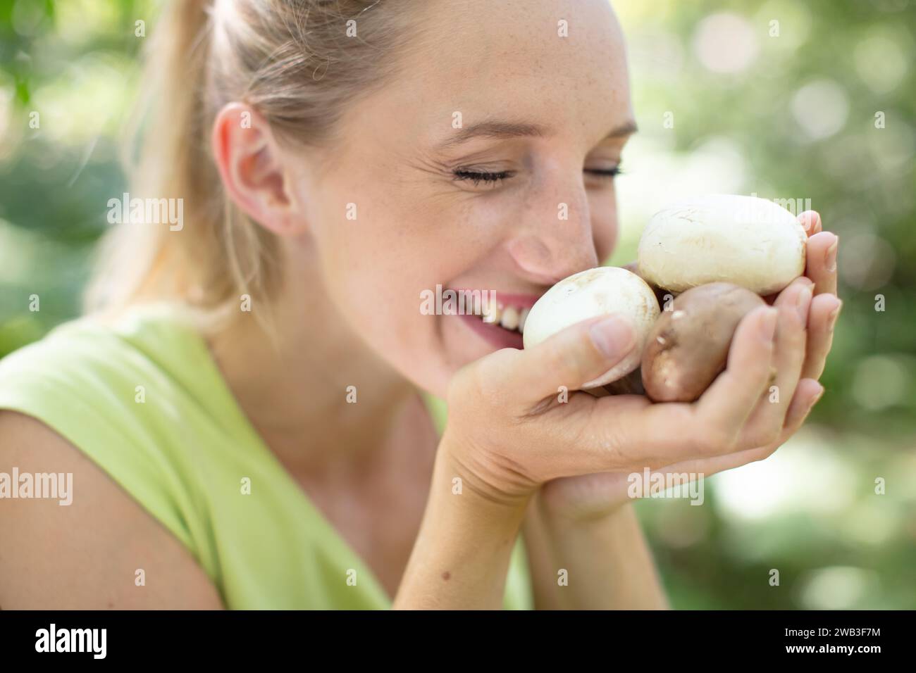 woman sniffing mushroom in forest Stock Photo