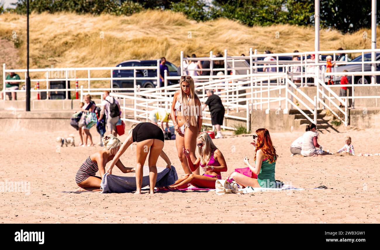 On a glorious hot day in Dundee, local women sunbathe along Broughty Ferry beach during the summer heatwave in Scotland, UK Stock Photo