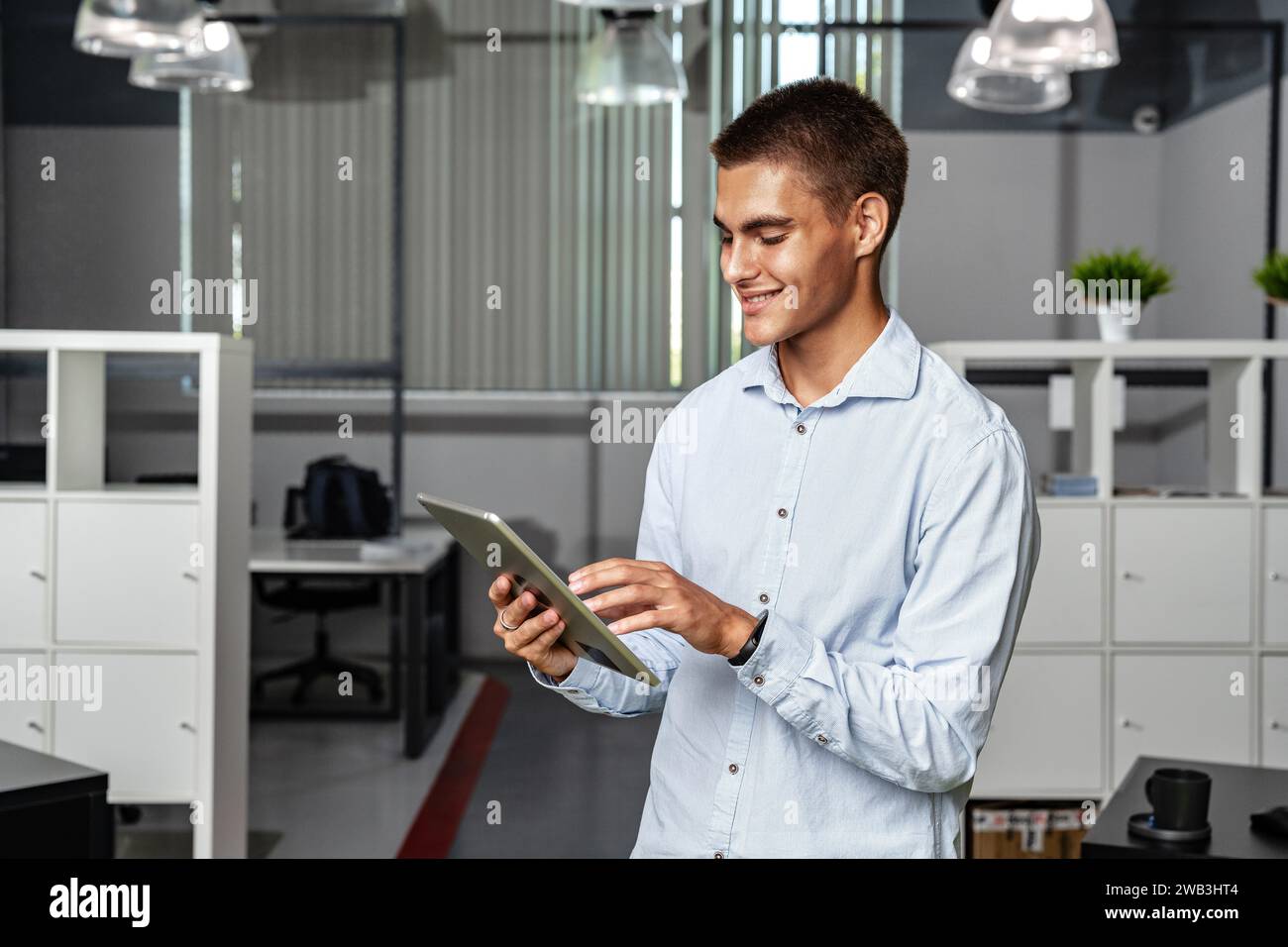 Young handsome businessman using digital tablet while standing in the office Stock Photo