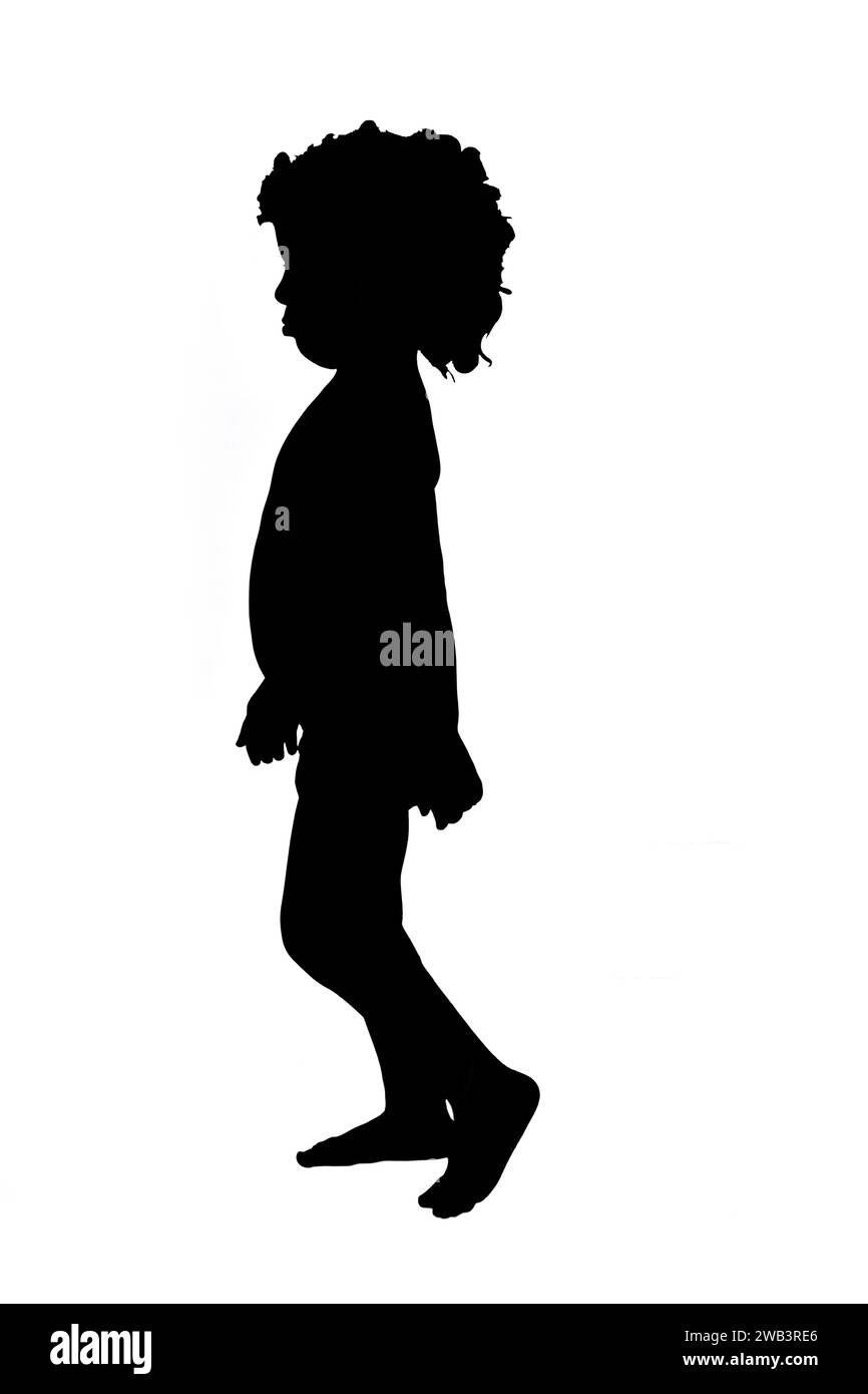 side view silhouette of a boy in shorts with curly hair walking on white background. Stock Photo