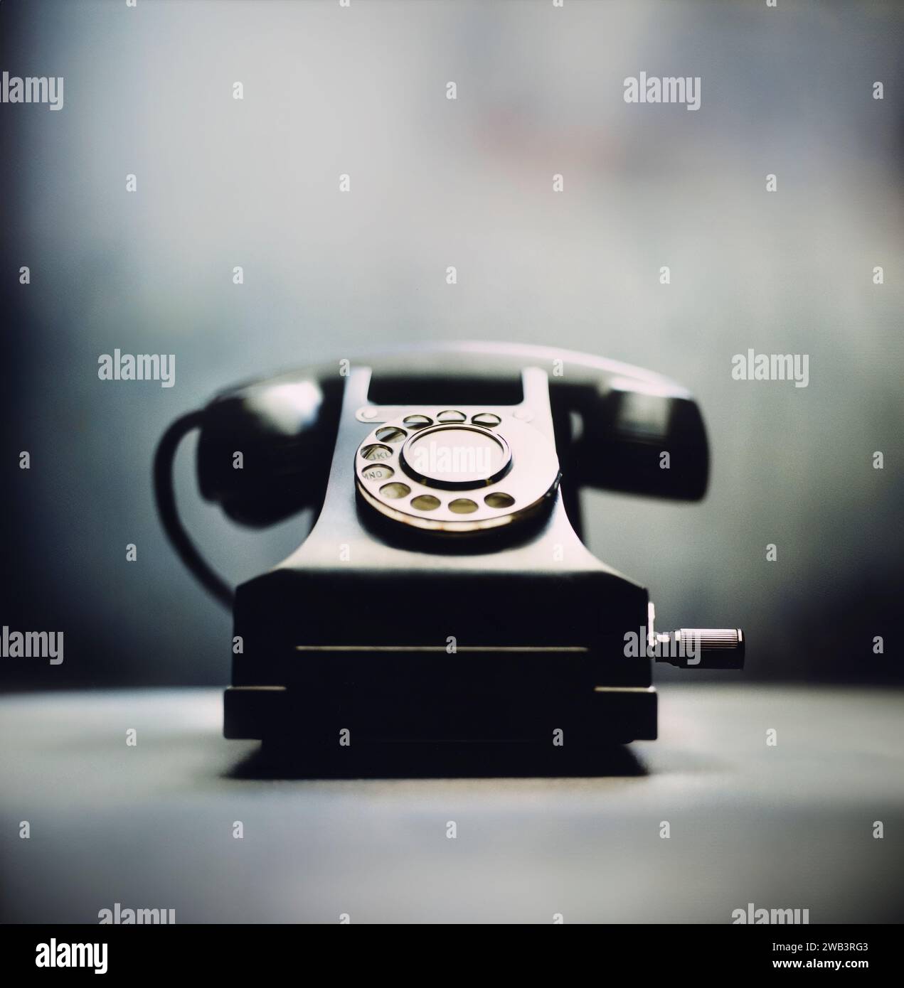 An antique telephone sits on a tabletop illuminated by natural light Stock Photo