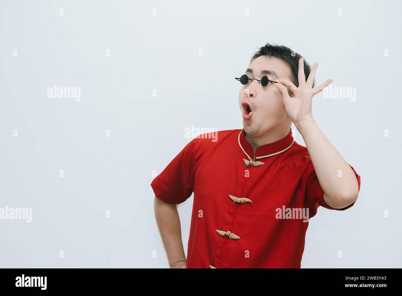Wow face of Asian man wearing Cheongsam and black vintage sunglasses while looking at the right side on white background Stock Photo