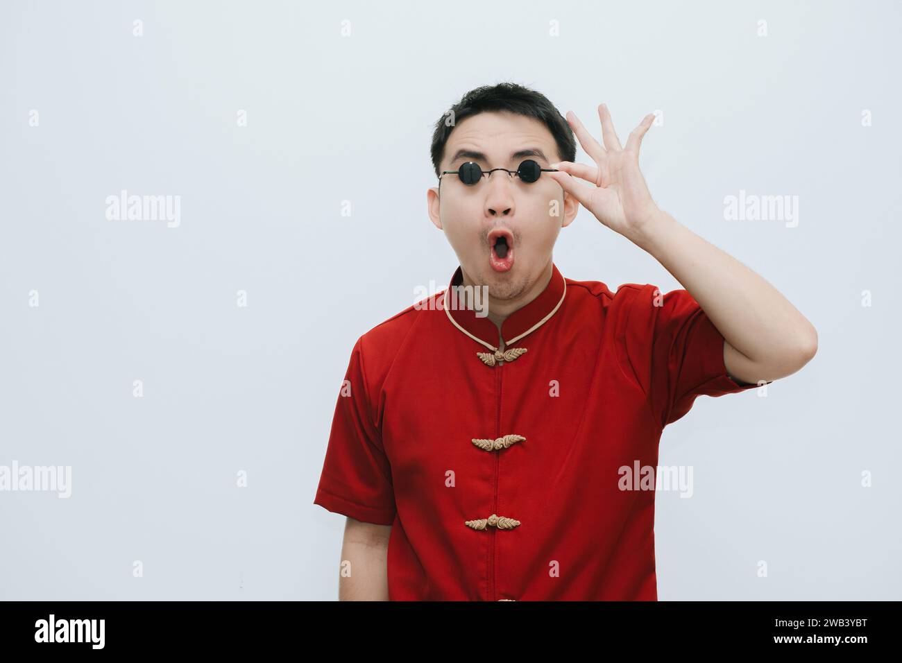 Wow face of Asian man wearing Cheongsam and black vintage sunglasses while looking at the camera on white background Stock Photo