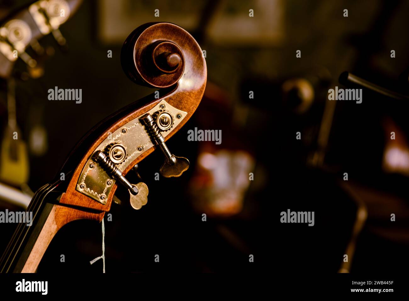 A close-up shot of an antique wooden violin, placed among several vintage guitars in a bright and airy music room Stock Photo