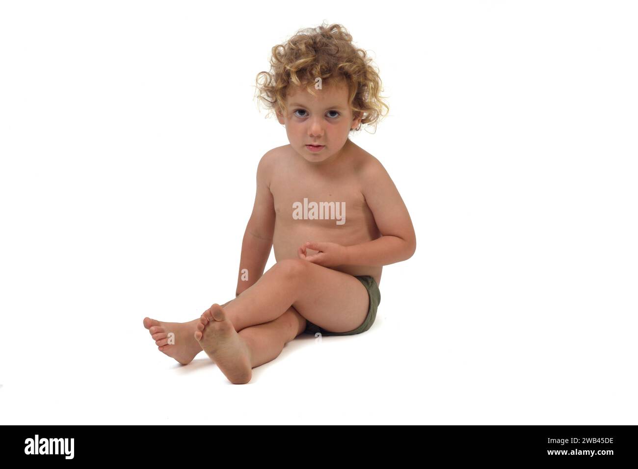 boy in underpants sitting on the floor looking at camera and cross legged on white background (3 year old) Stock Photo