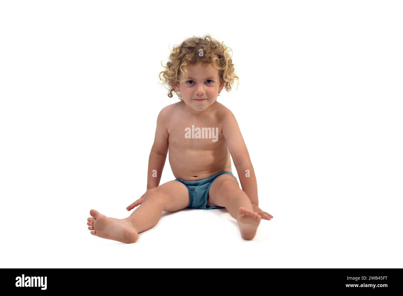front view of boy in underpants sitting on the floor looking at camera on white background (3 year old) Stock Photo