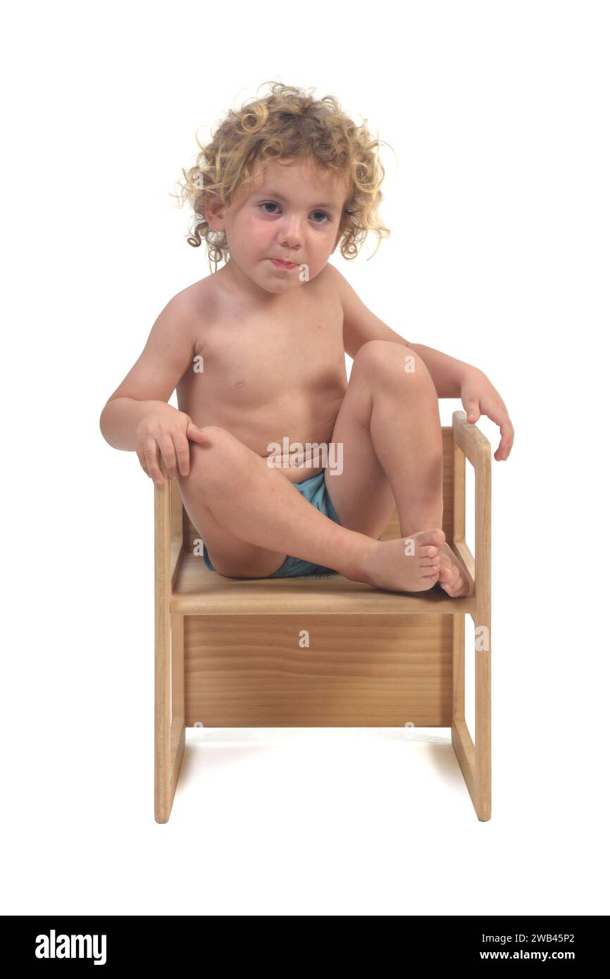 front view of a  boy sitting on top of a chair  on white background (3 year old) Stock Photo