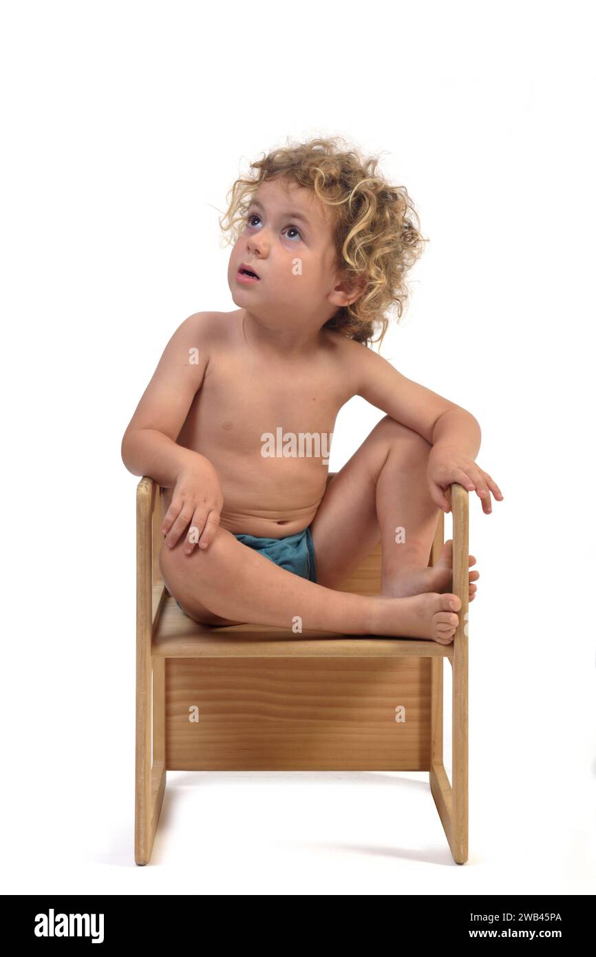 front view of a  boy sitting on top of a chair and looking up on white background (3 year old) Stock Photo