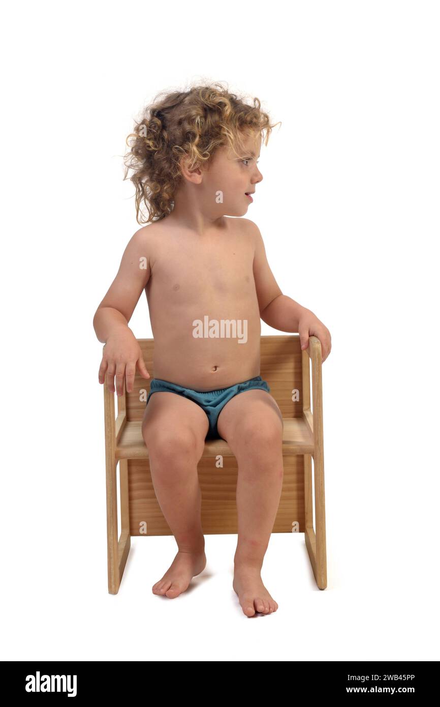 front view of a boy in underpants sitting on chair and look side on white background (3 year old) Stock Photo