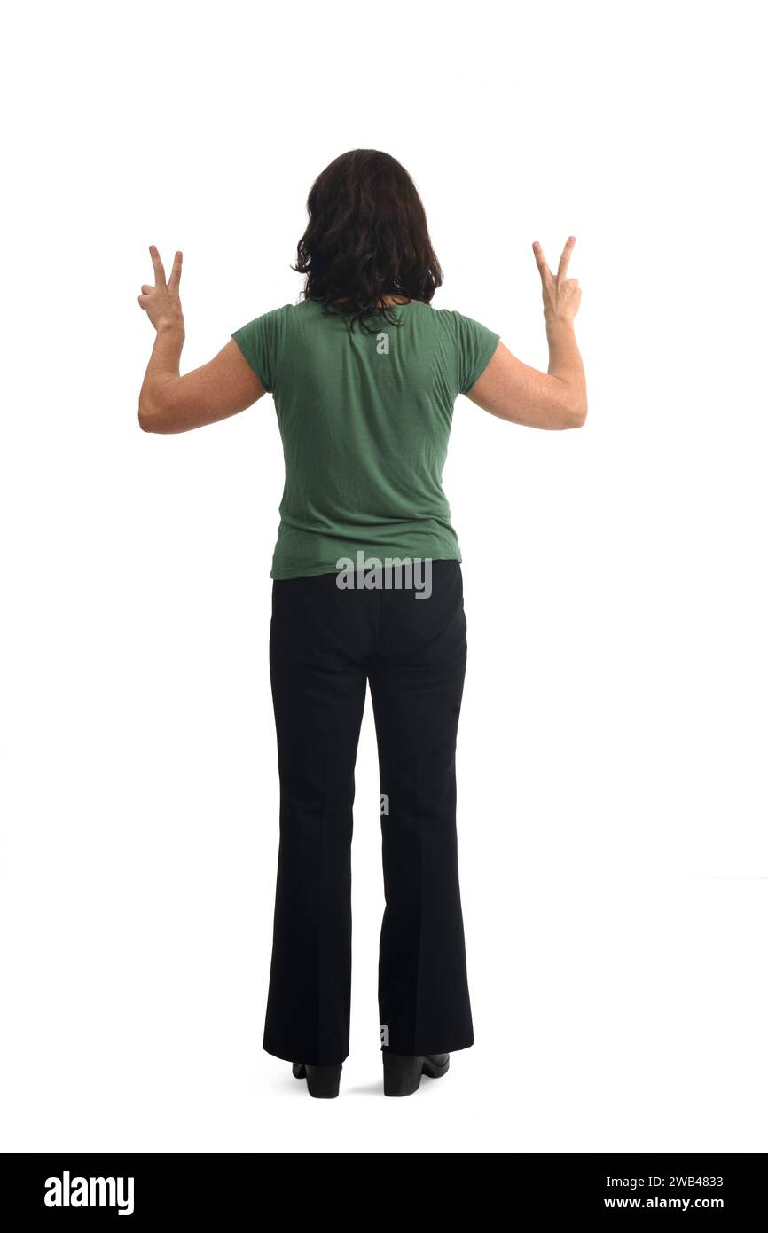 back view of a woman raising two arms showing the victory sign with her fingers on white background. Stock Photo