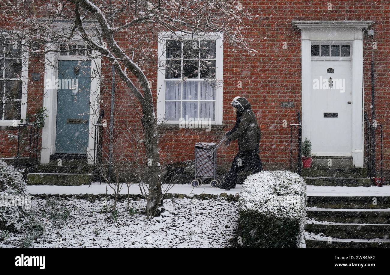 People walking through a snow flurry in Lenham, Kent. Sleet and snow showers have been forecast for parts of the country on Monday as some regions are still trying to grapple with flooding following intense rainfall. Picture date: Monday January 8, 2024. Stock Photo
