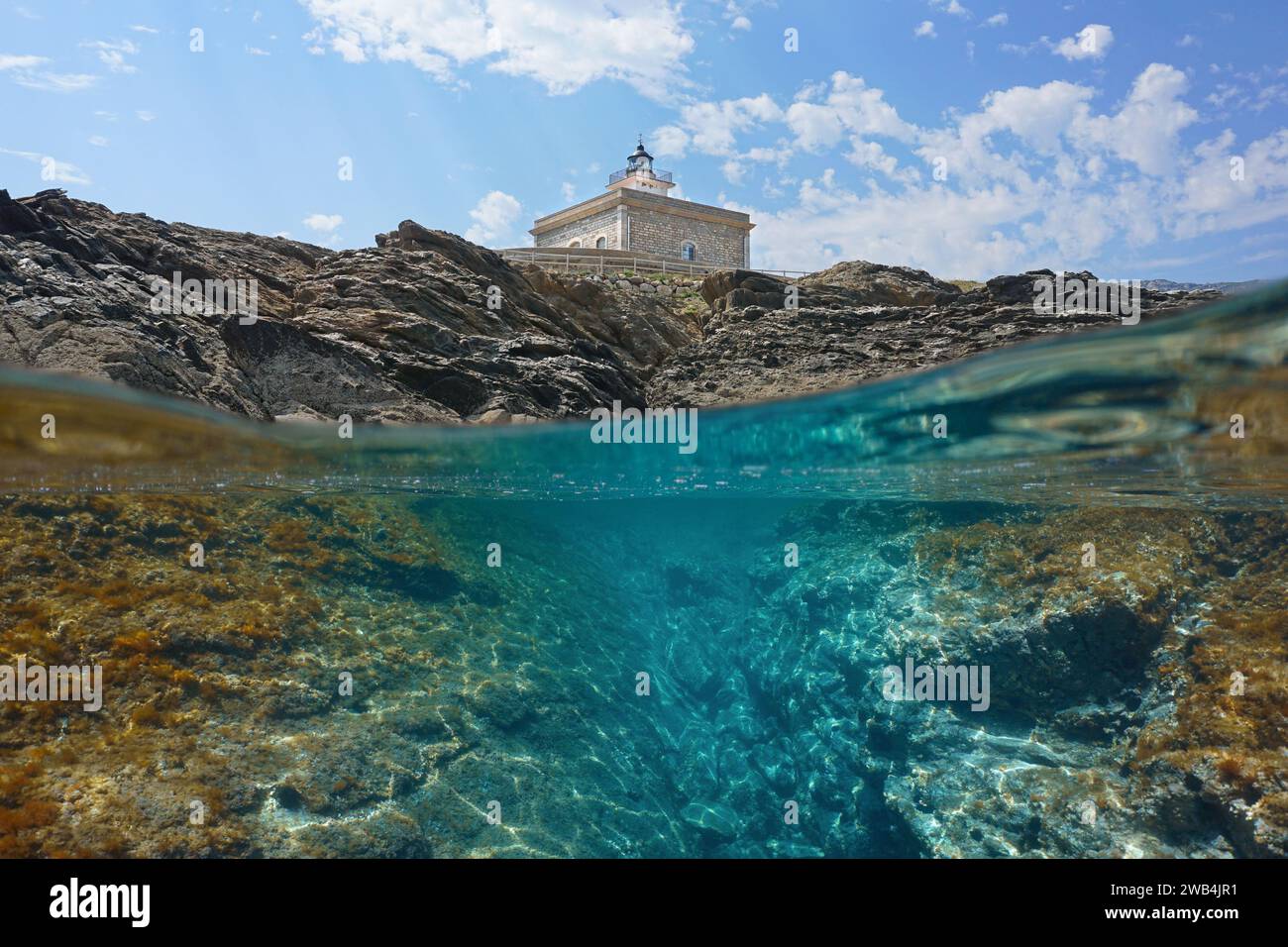 Lighthouse on the Mediterranean coast in Spain with rocky shore over and under water surface, split level view, natural scene, Costa Brava, Catalonia Stock Photo