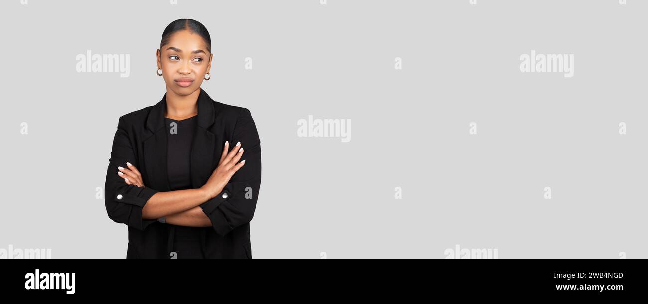 Skeptical African American businesswoman stands with arms crossed Stock Photo