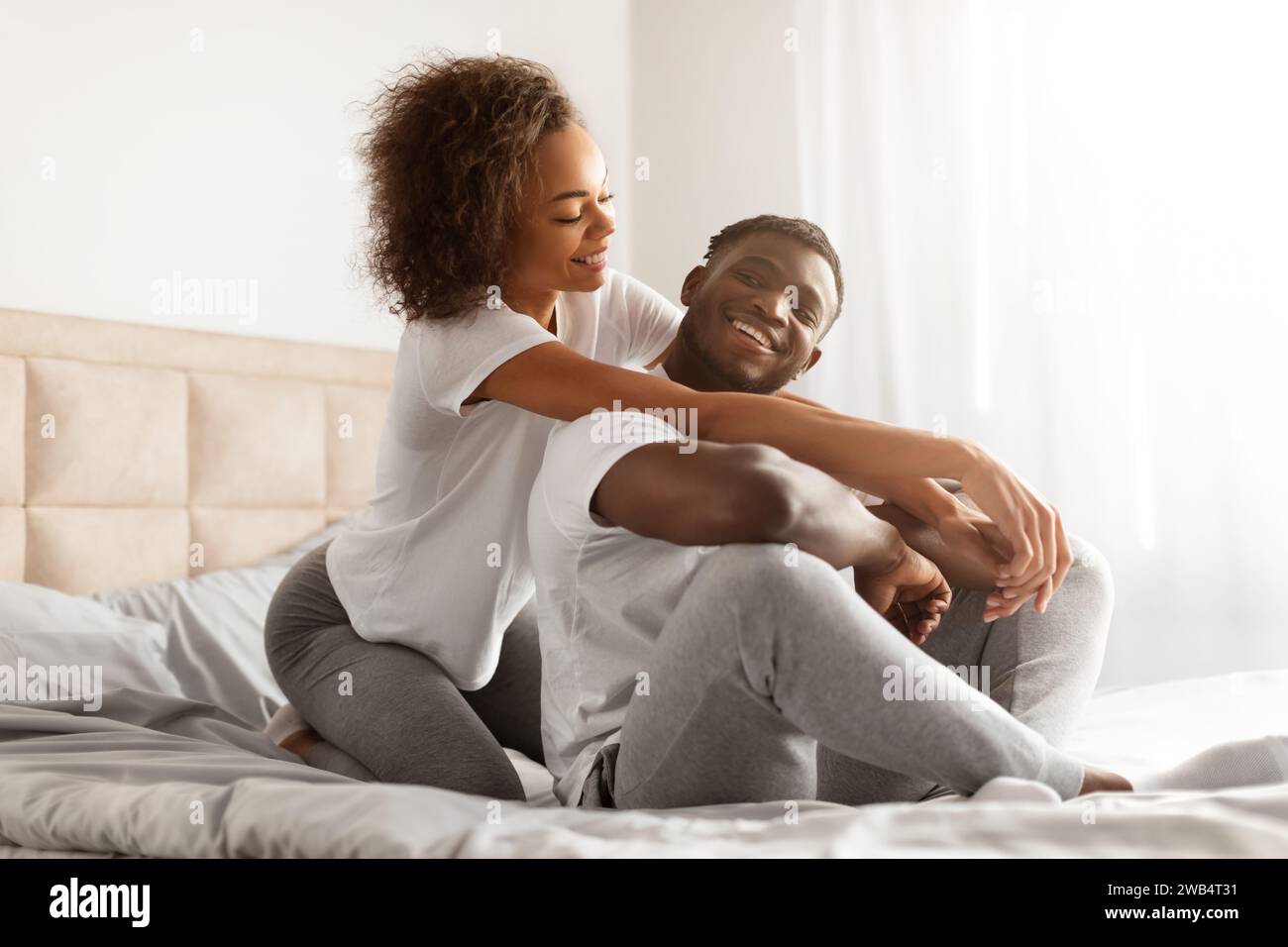 Loving Black Woman Hugging Her Husband Sitting On Bed Indoor Stock ...