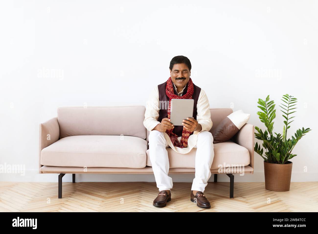 Relaxed mature eastern man chilling at home, using tablet Stock Photo