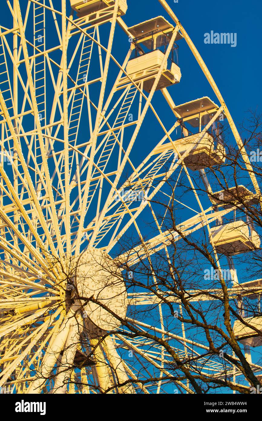 Ferris wheel against a clear blue sky with sunlight casting shadows, conveying a sense of leisure and entertainment in Lancaster. Stock Photo
