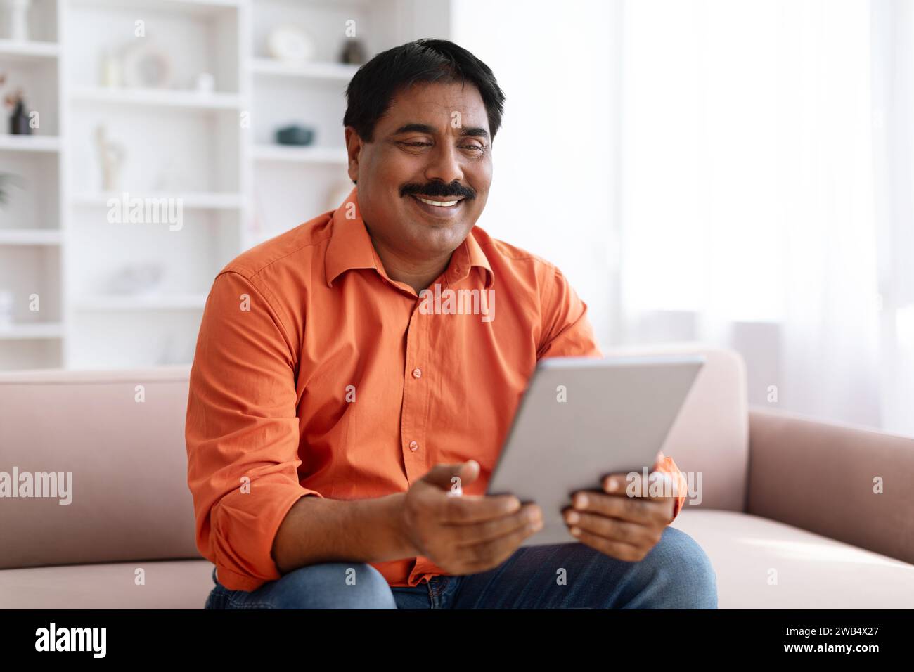Positive indian man using digital tablet at home Stock Photo