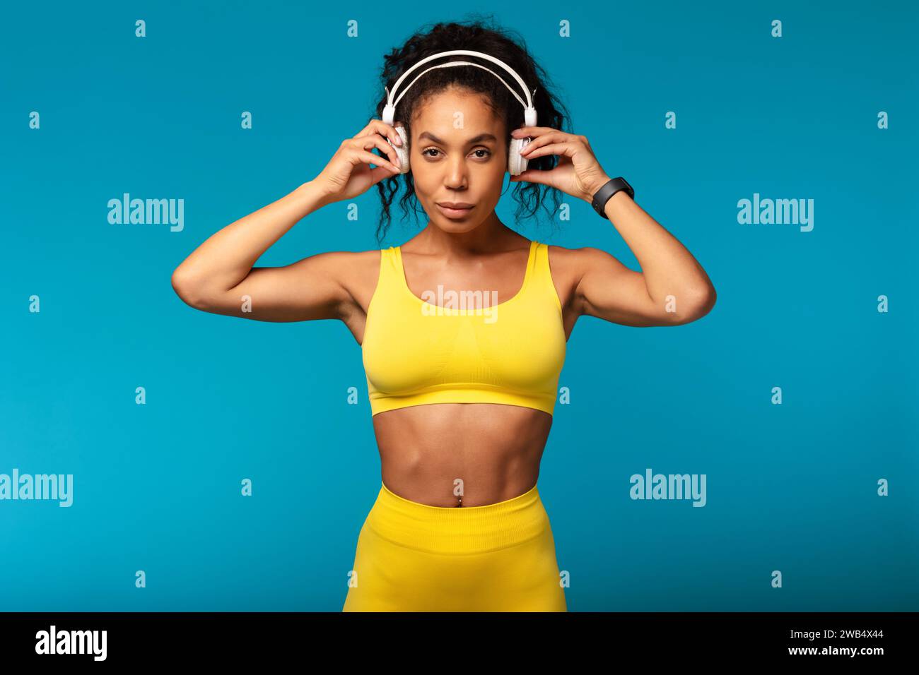 Fit black lady using wireless headphones while training in studio Stock Photo