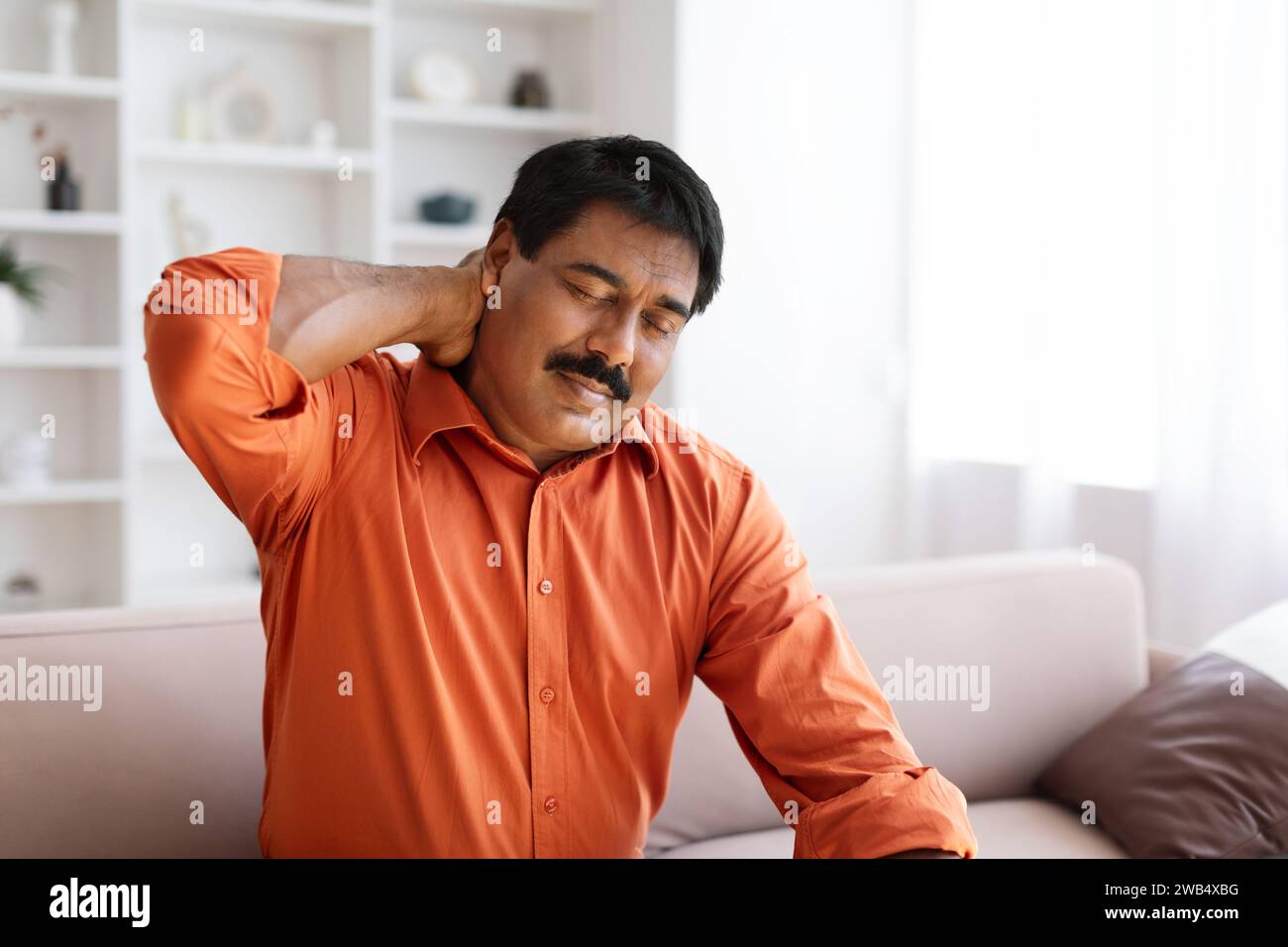 Suffering middle aged indian man feeling neck pain Stock Photo - Alamy