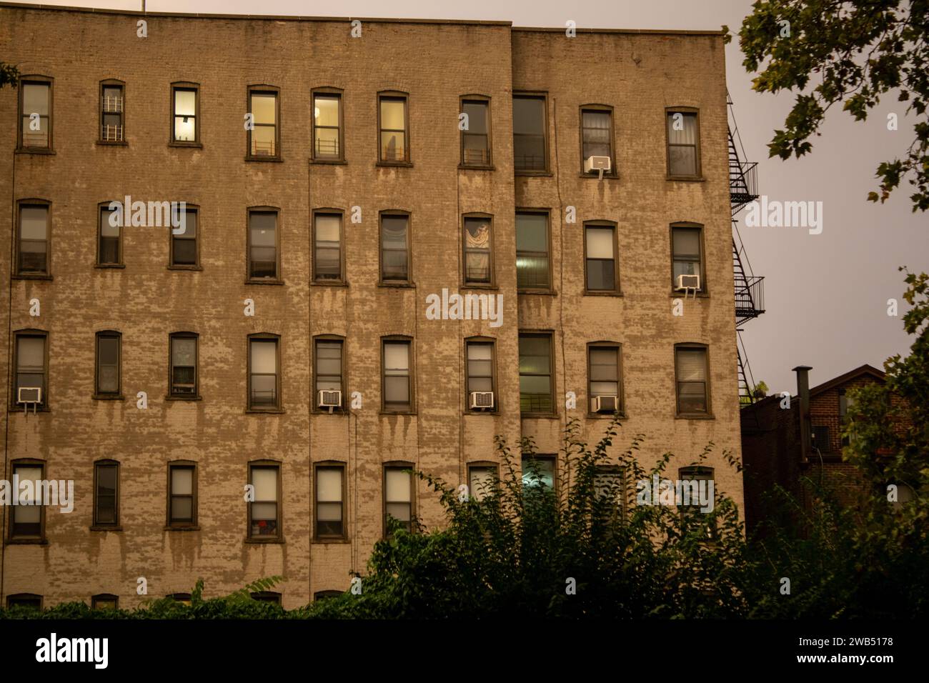 This image is of a tall brick building with numerous windows adorning its facade Stock Photo