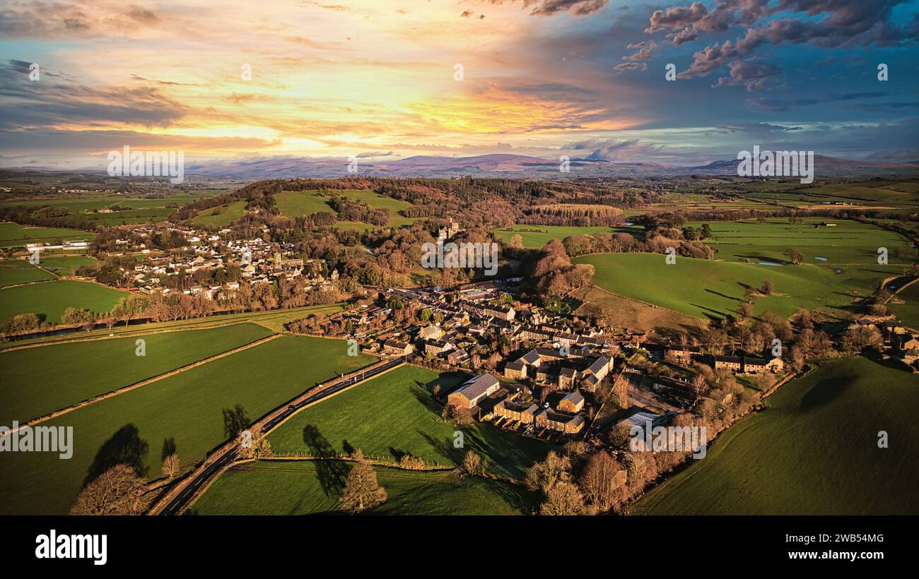Aerial view of a quaint village amidst green fields during sunset with ...