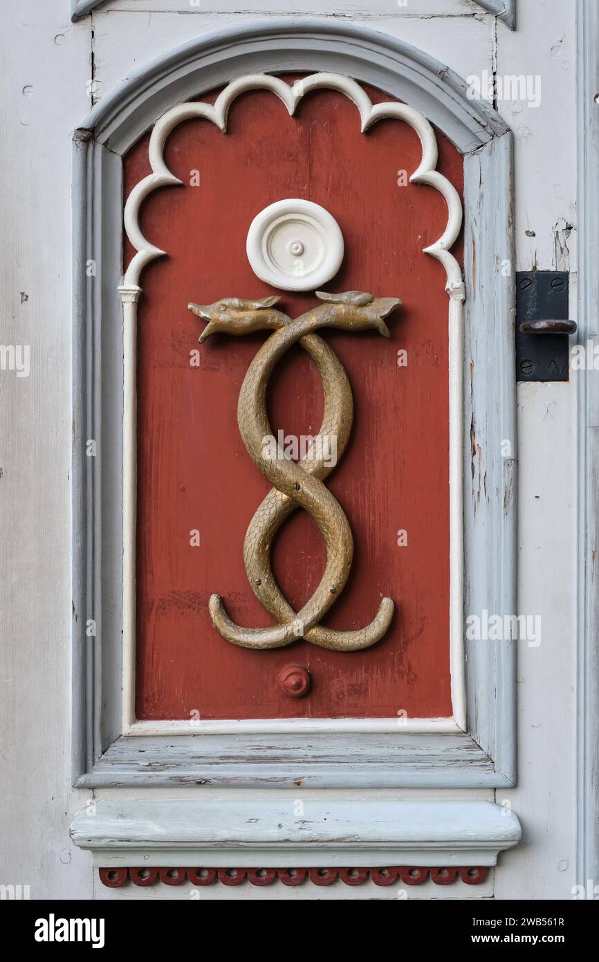 Old medicine symbol of old pharmacy. Retro emblem of medicine - two snakes, caduceus, signboard on a wooden door. Stock Photo