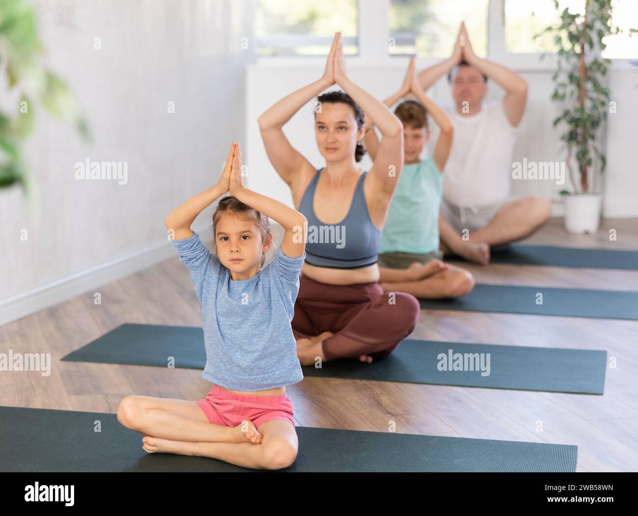 Mom with her family practices yoga in lotus position Stock Photo - Alamy