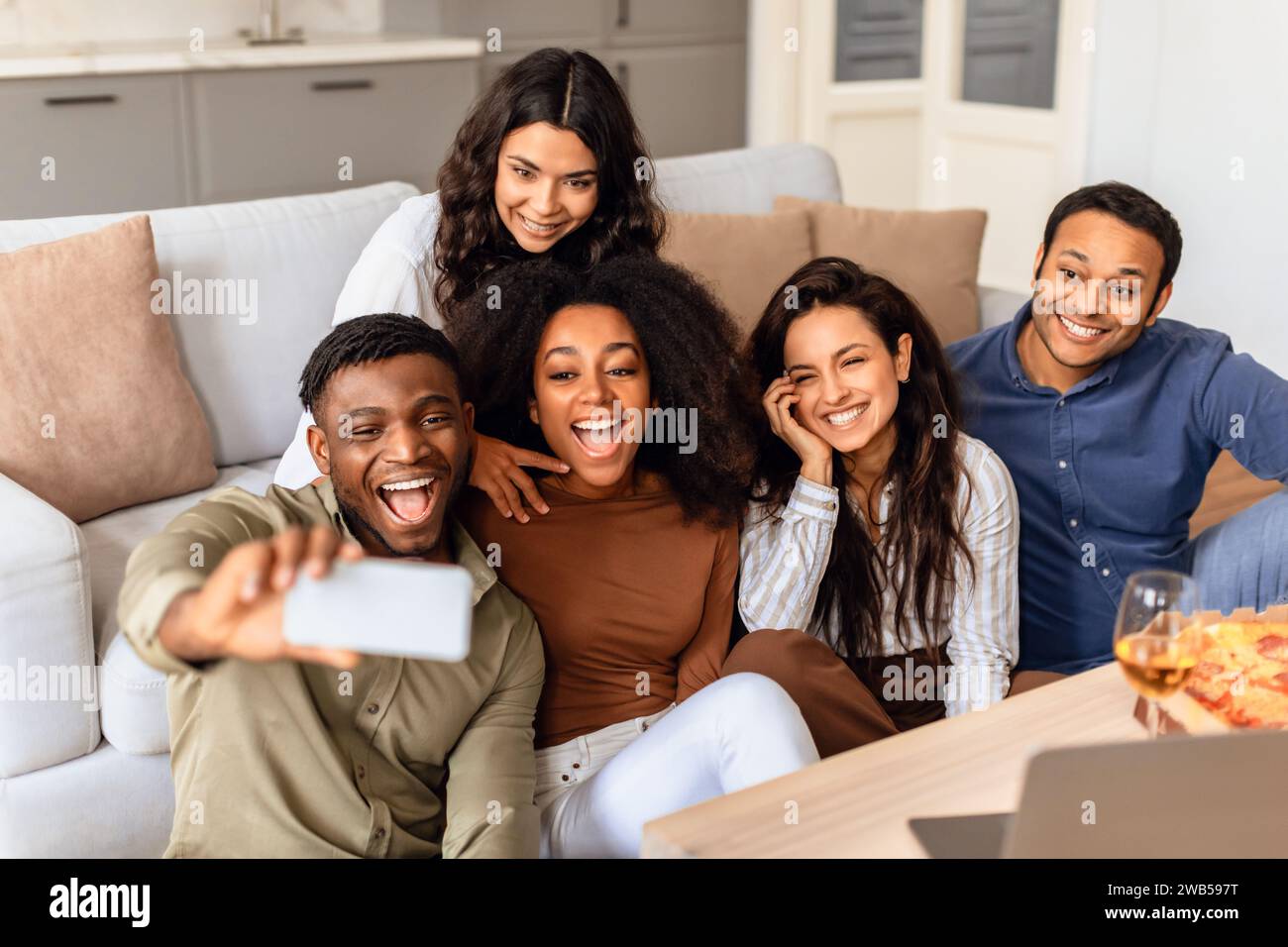 diverse friends taking selfies on mobile phone in living room Stock Photo
