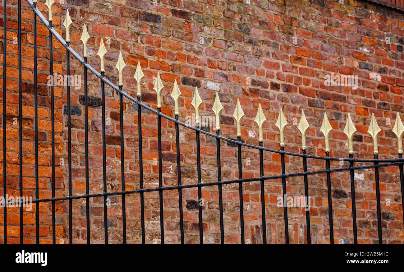 Gold and black iron gate against old brick wall, Hull, UK Stock Photo