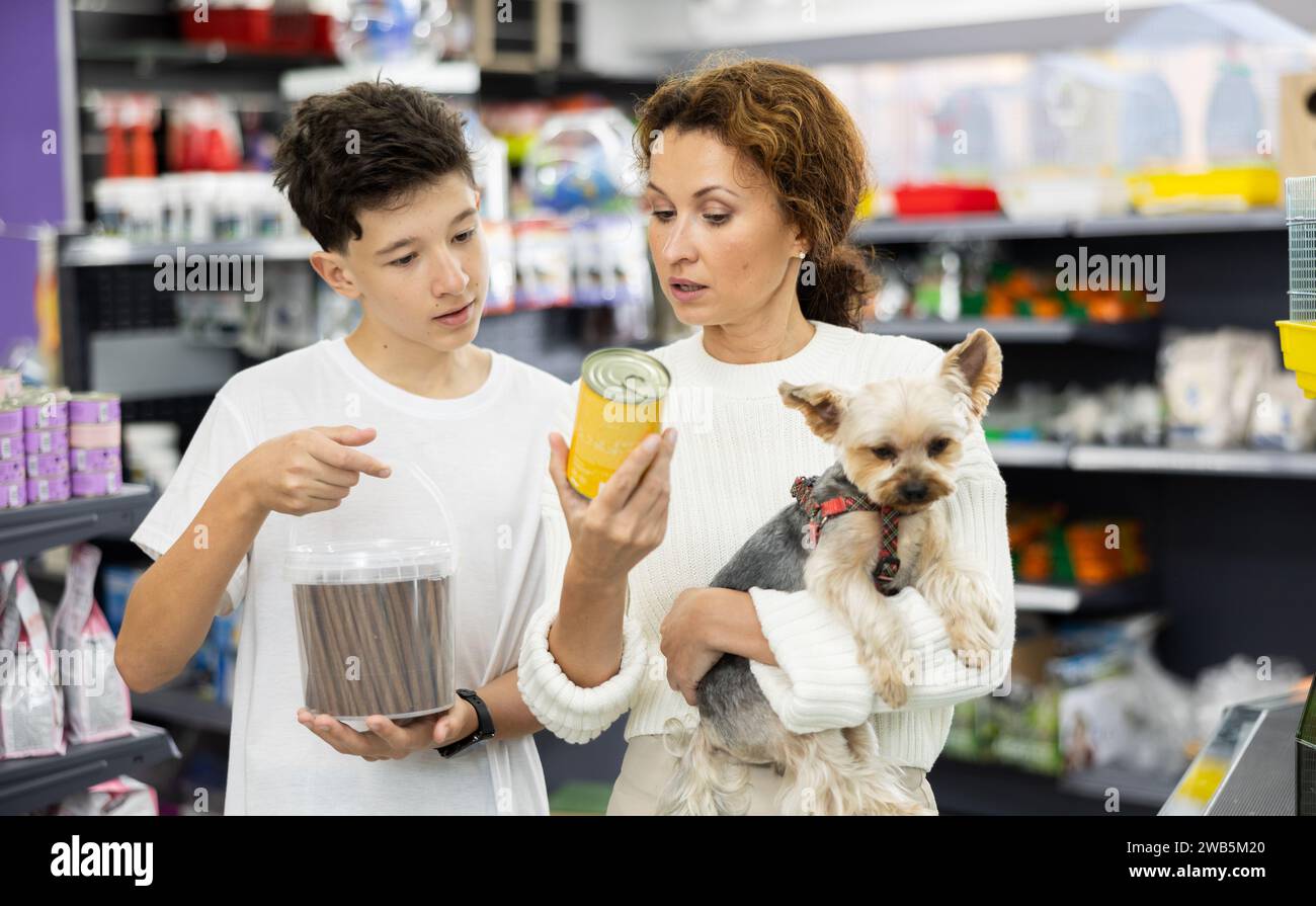 Mother with dog Yorkshire Terrier in arms and son carefully examine label on dry dog food Stock Photo
