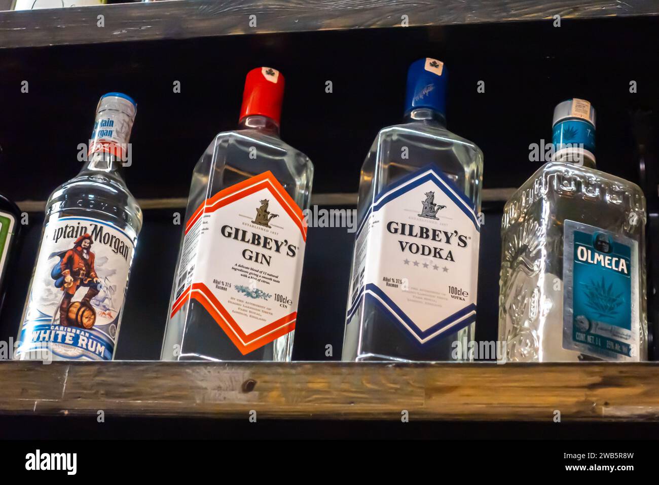 Gilbey's Gin, Gilbey's vodka, Captain Morgan white rum. tequila Olmeca bottles on a bar shelf Stock Photo