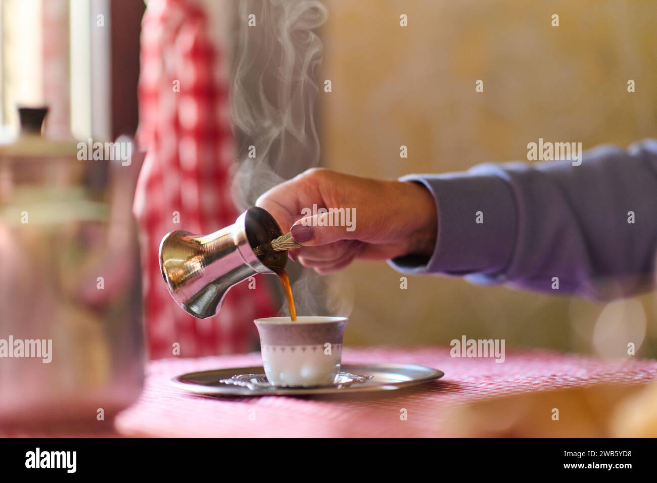 Elderly woman savors the serenity of the morning as she enjoys a cup of coffee on the porch of her rustic cottage, finding solace in the simplicity of Stock Photo