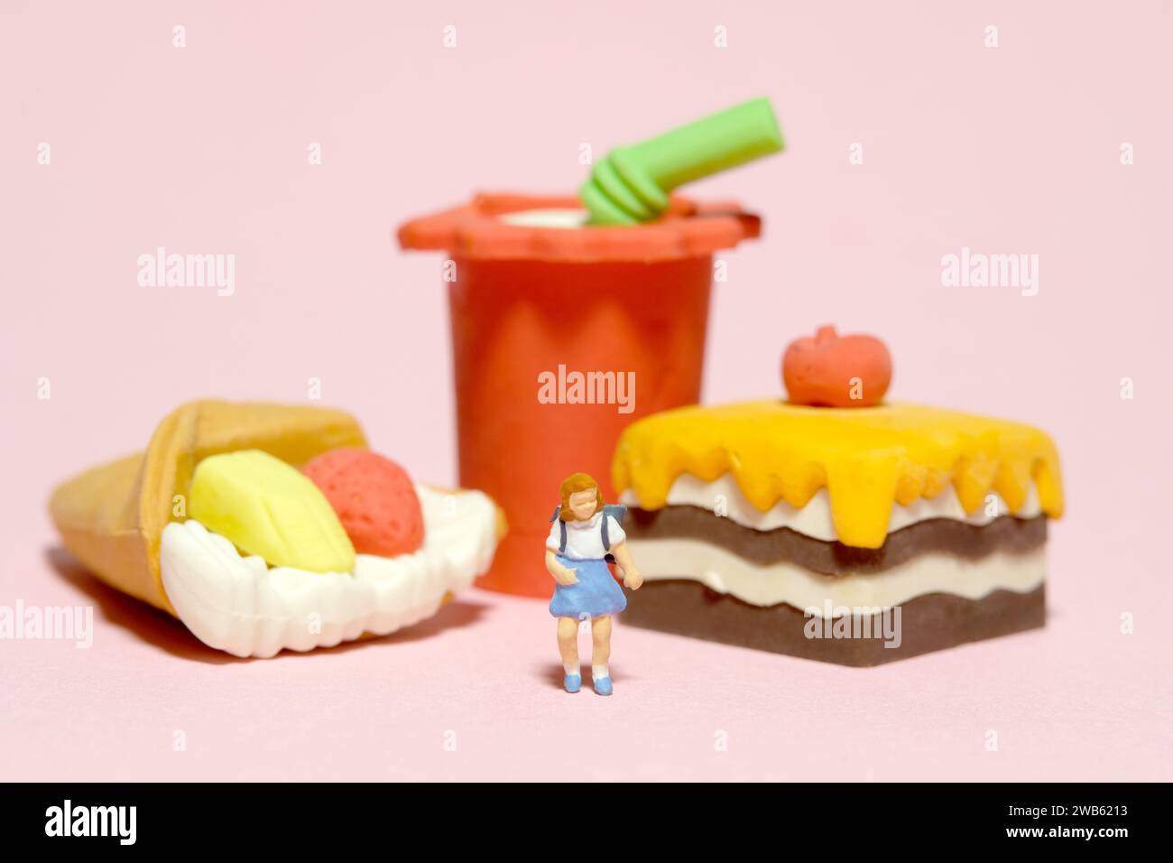 Miniature people toy figure photography. Healthy food eat and lunch break concept. A girl kindergarten student standing in front of cake and soft drin Stock Photo