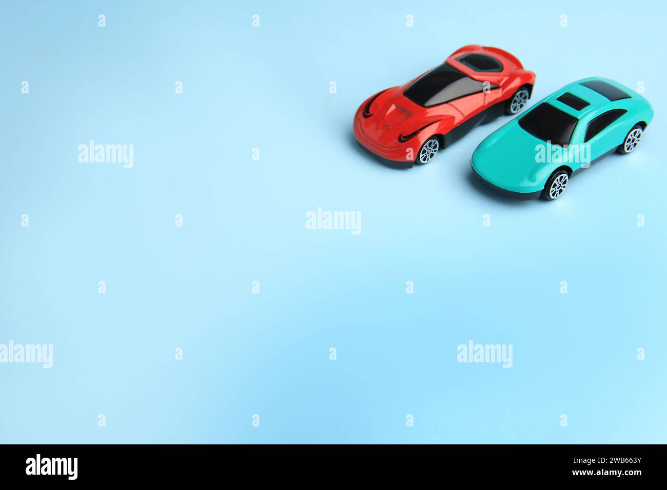 Two bright cars on light blue background, space for text. Children`s ...