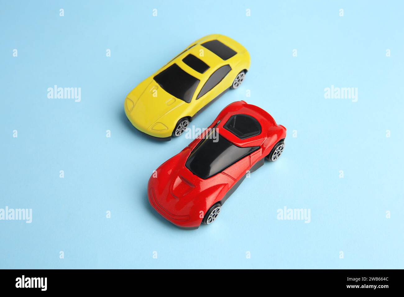 Two bright cars on light blue background, above view. Children`s toys ...