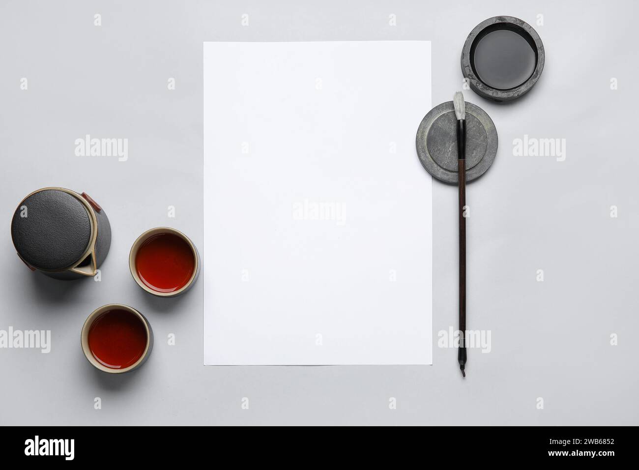 Composition with blank sheet of paper, ink, brush and cups of tea on ...