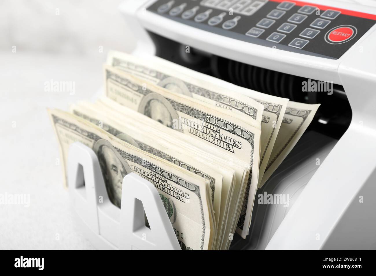 Modern cash counting machine with dollar banknotes on light background ...